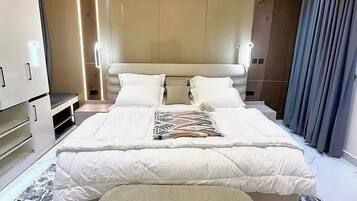 Habitación de hotel moderna con una cama grande, una mesita de noche, un armario y una zona de estar.