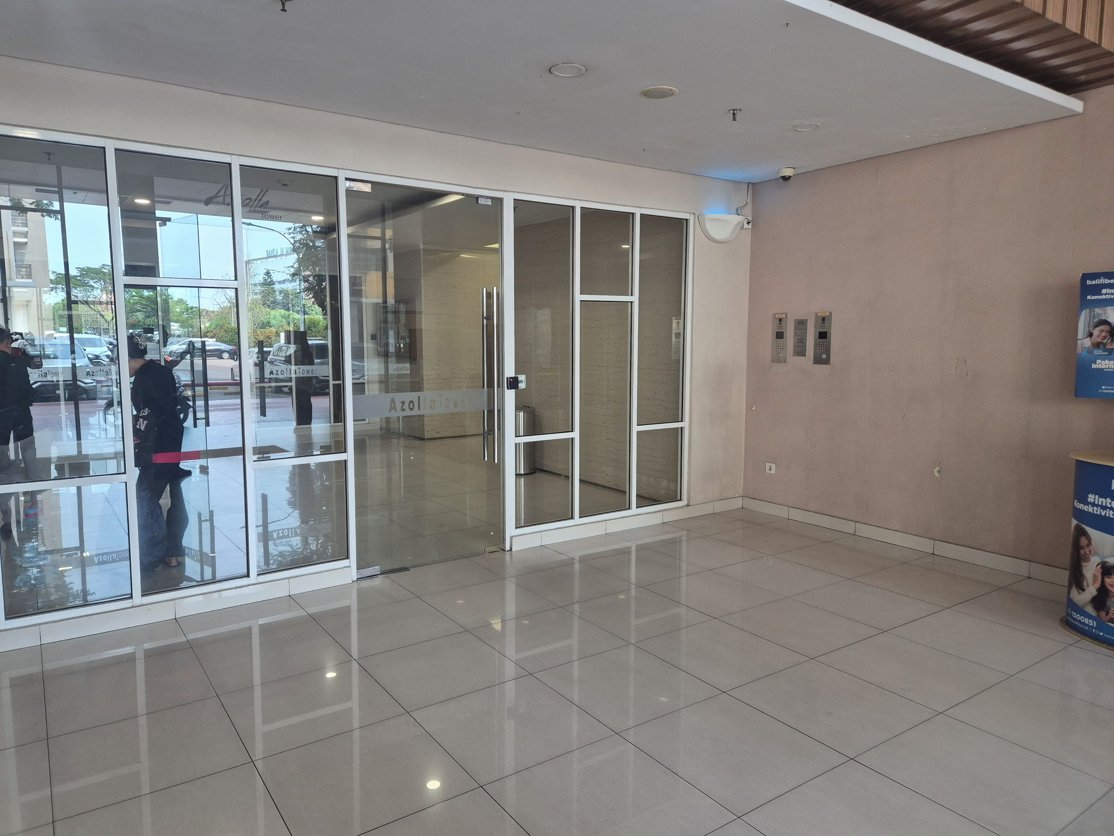 A lobby with a glass door entrance, a tiled floor, and a wall-mounted elevator.