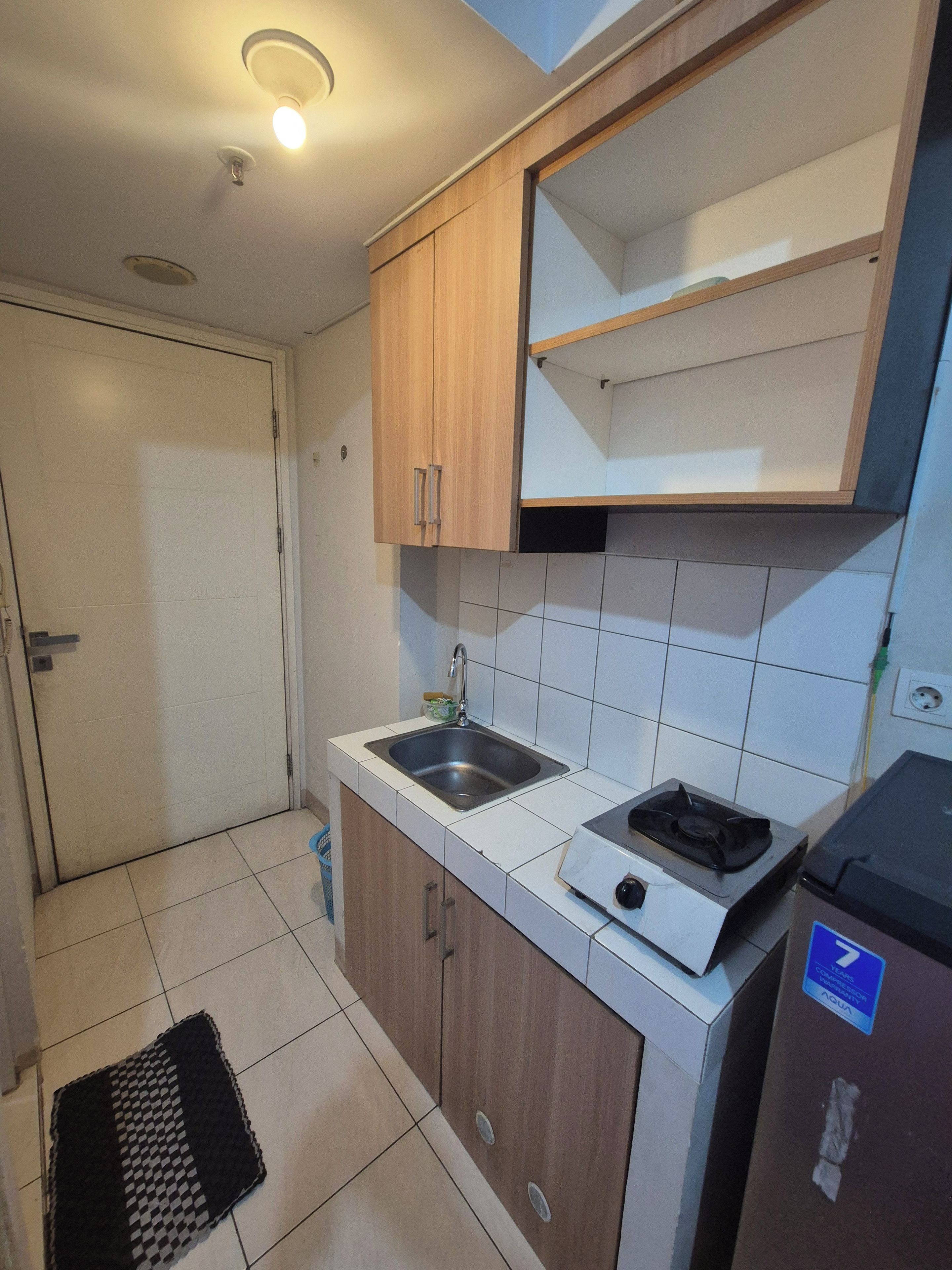 Una cucina compatta con lavello, fornelli e pensili in legno.