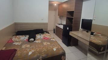 A bedroom with a bed, a desk, a mirror, and a ceiling light.