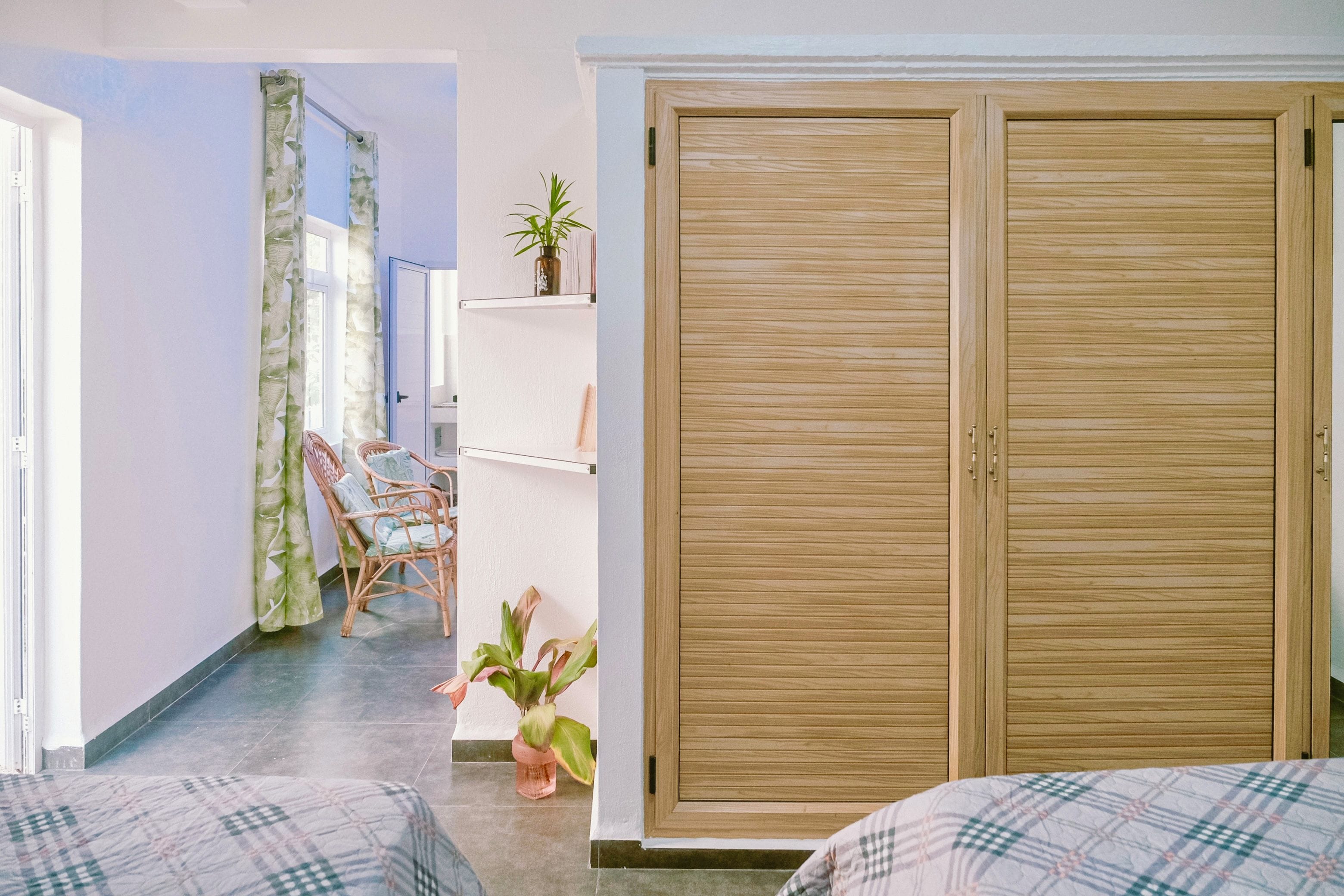 Ein Zimmer mit einem Bett, einem Kleiderschrank, einem Sessel und einer Zimmerpflanze.