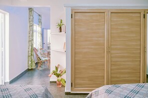 A room with a bed, a wardrobe, a chair, and a potted plant.