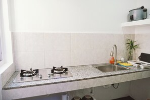 A kitchen with a double sink, two gas stoves, a stainless steel faucet, and a potted plant on the counter.