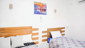 Ein Zimmer mit zwei Holzbetten, weißen Wänden und einem Sonnenuntergangsbild.