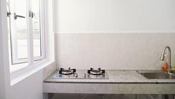 A kitchen with two gas stoves, a stainless steel sink, and a window with white frames.