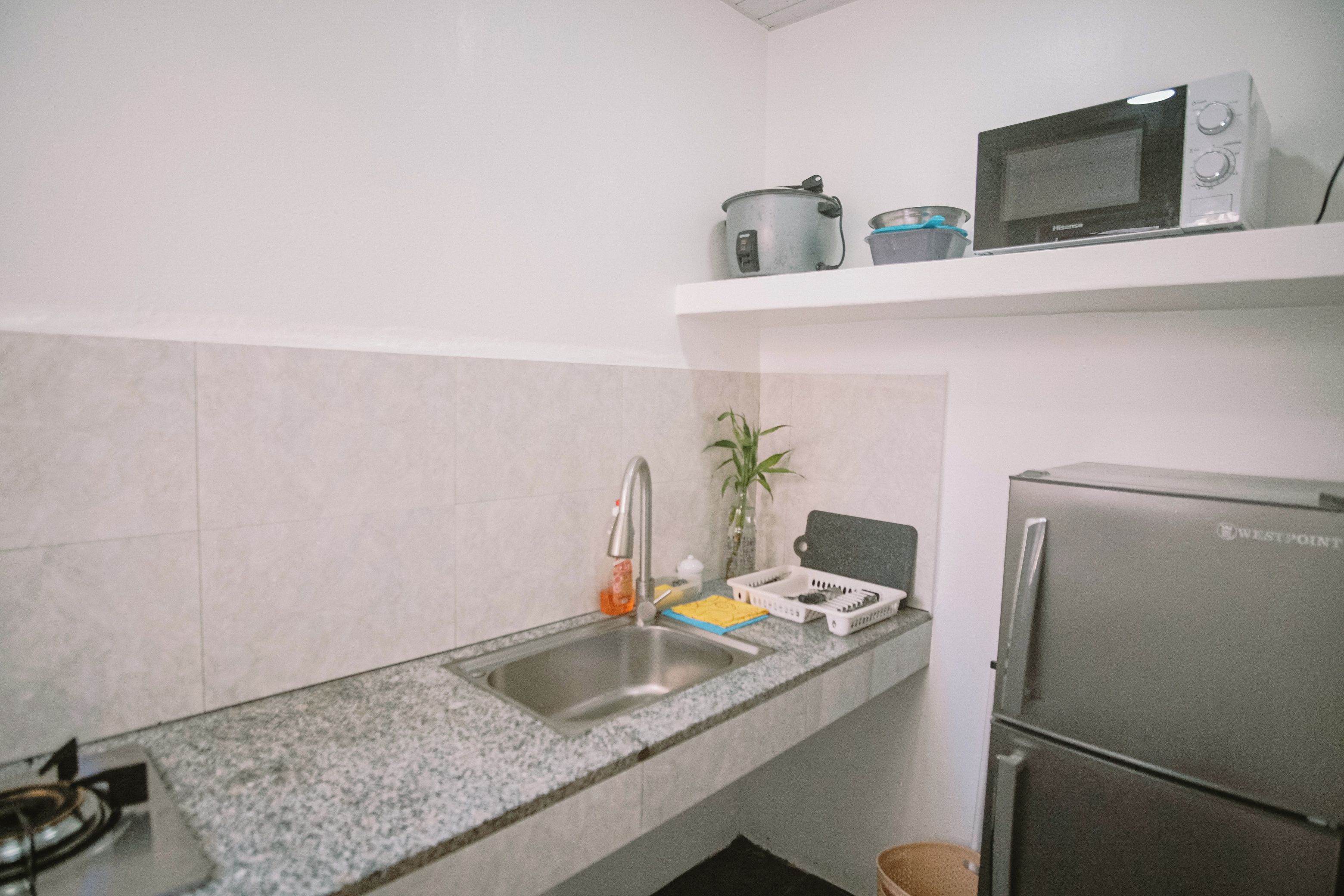 Una cucina con lavello in acciaio inossidabile, forno a microonde, piano cottura e frigorifero.