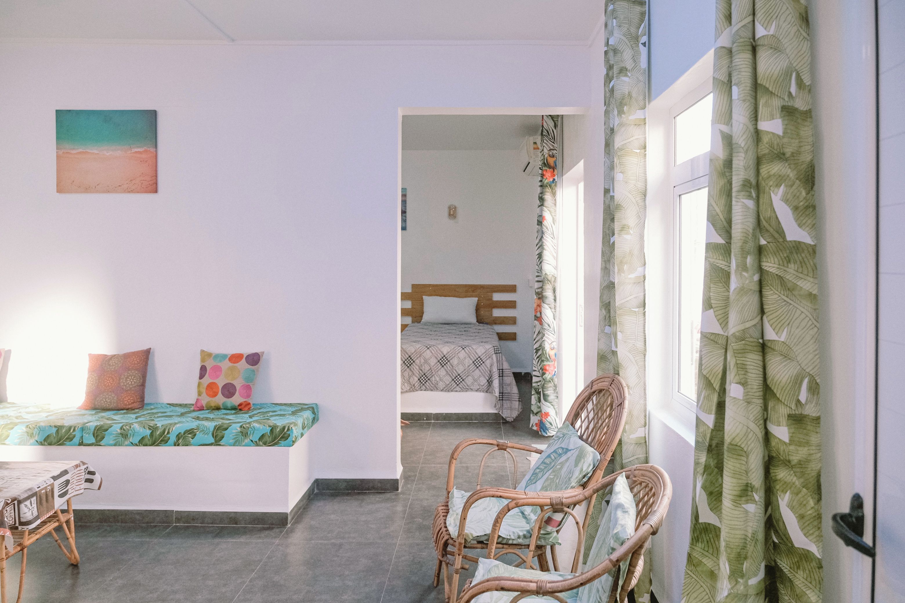 Een kamer met een bed, een stoel, een tafel en een schilderij aan de muur.