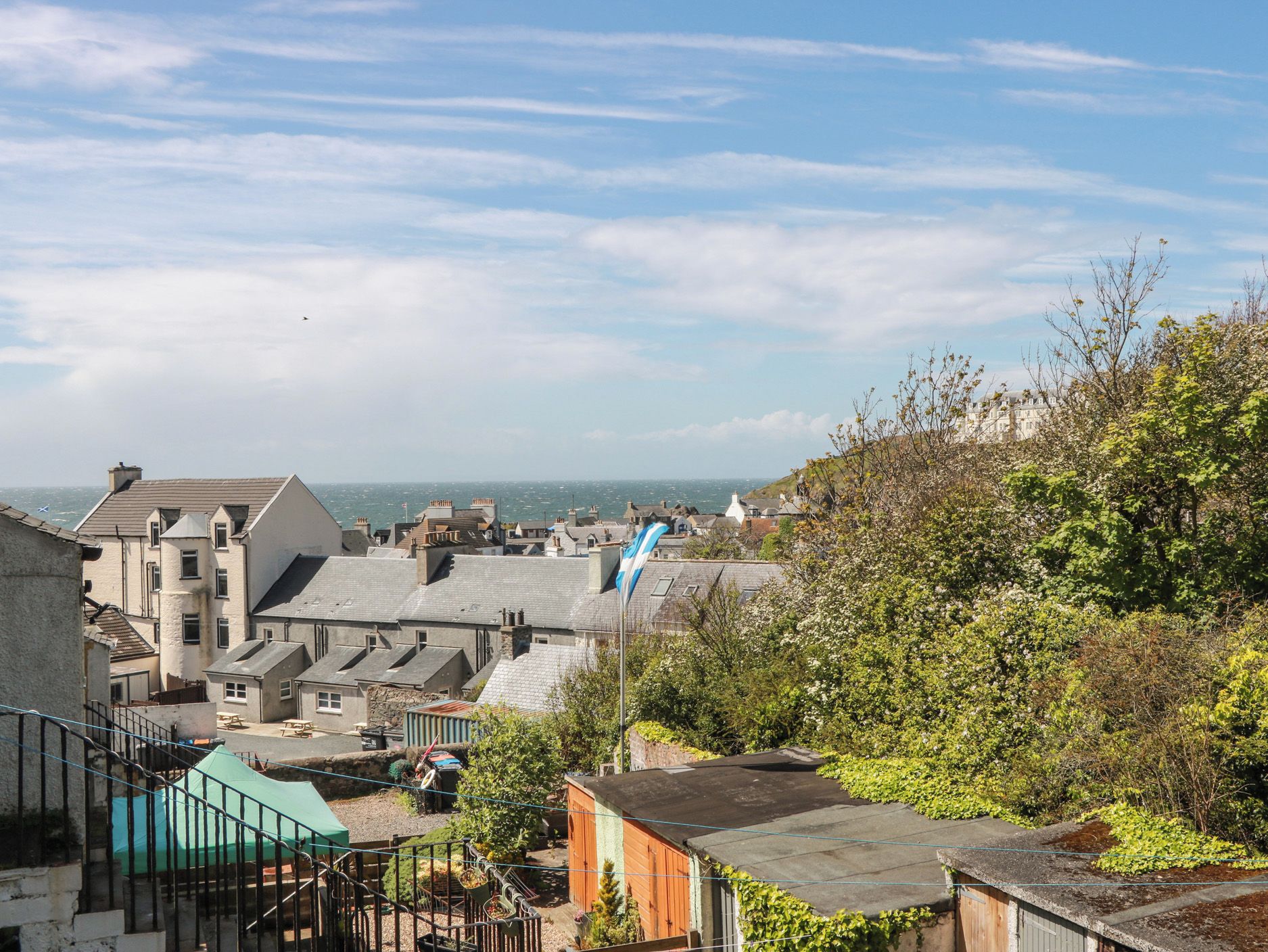 A coastal town with buildings, a flag, and a view of the sea.
