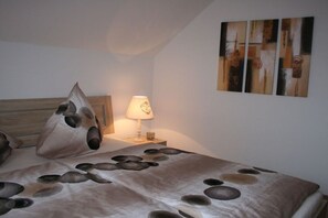 Un dormitorio con cama, mesita de noche, lámpara y decoración abstracta en la pared.