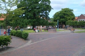 Un'area esterna pavimentata con panchine e alberi, circondata da edifici.