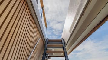A wooden exterior wall with a metal ladder leading to a window.