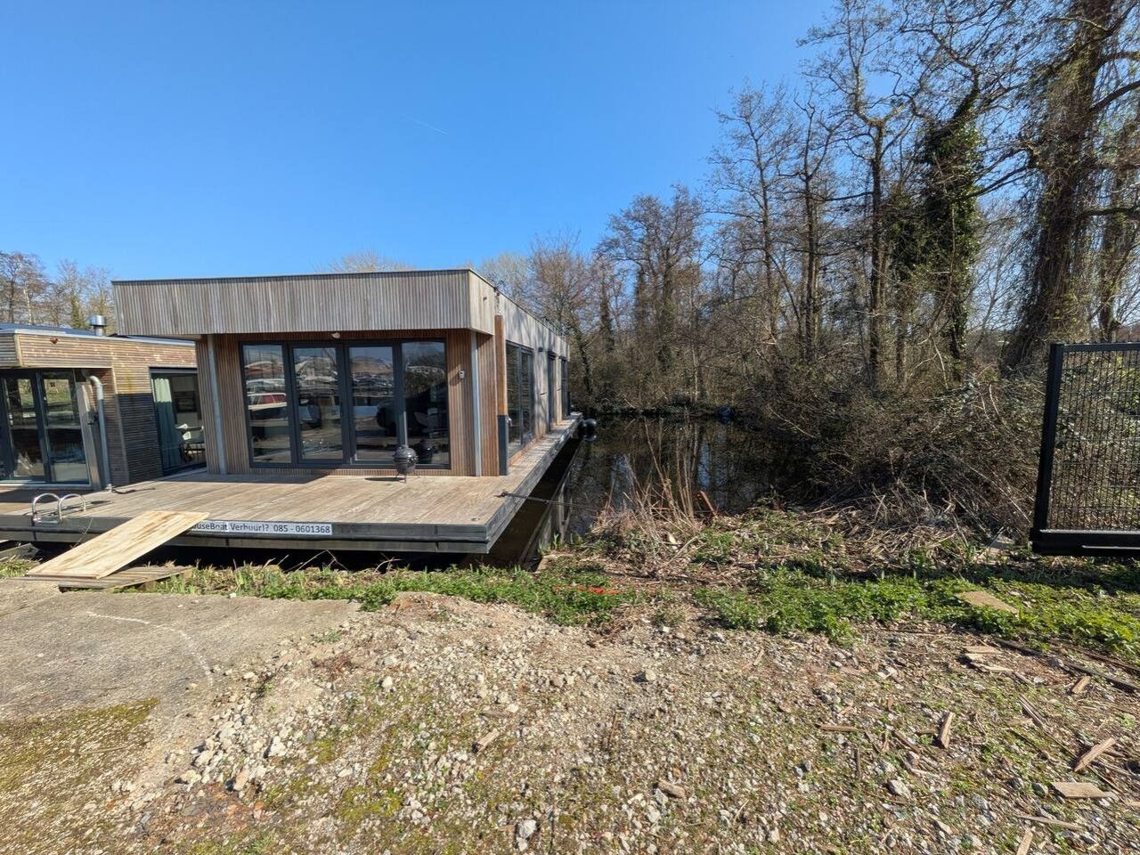 Un edificio moderno con techo plano, ventanas amplias y una terraza de madera.