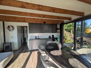 A modern kitchen with a central island, wooden beams, and a view of the outdoors.