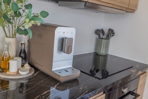 A kitchen with a coffee maker, a plant, and various kitchen utensils.