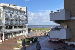 A hotel with a balcony overlooking the beach, outdoor seating, and a clear view of the sea. - Luca Panorama Apt. 227, 1st floor (Cuxhaven)