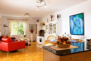 A modern kitchen with a dining area, a red sofa, and a fruit bowl on the counter. - Bungalow with 1 bedroom (Playa Blanca)