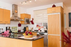 Eine moderne Küche mit Holzausstattung, einer Edelstahl-Dunstabzugshaube, einer Mikrowelle und einem Kühlschrank.