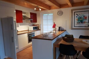 A kitchen with white cabinets, a red oven, a microwave, and a wooden island with a sink. - Holiday home with 3 bedrooms (Krummhörn*\/Greetsiel)