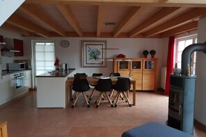 Eine moderne Küche mit Essbereich, Holzbalkendecke und integriertem Herd.