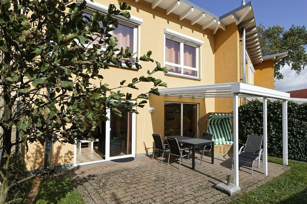 Une maison avec un patio, une table et des chaises.