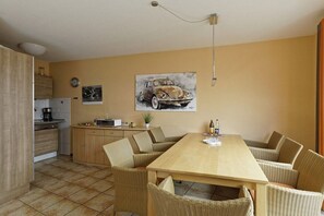 A compact kitchen with a dining area featuring a wooden table and wicker chairs. - Weser Residential Park, House 9 (Cuxhaven)