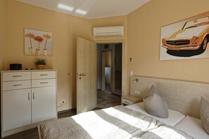 A bedroom with a bed, bedside table, and a wall-mounted air conditioner. - Weser Residential Park, House 9 (Cuxhaven)