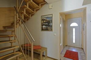 A wooden staircase leading to a landing with a red cushion on a small table. - Weser Residential Park, House 9 (Cuxhaven)