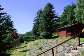 A cabin with a wooden exterior, surrounded by a forested landscape and a stone staircase leading up to it. - Holiday home with 2 bedrooms (Schönbrunn)