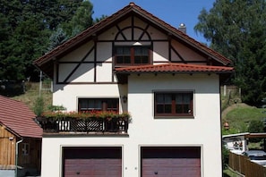 A two-story house with a gabled roof and a balcony with flower boxes. - Holiday home with 2 bedrooms (Schönbrunn)