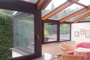 A room with a large skylight, a wicker chair, and a small table. - Holiday home with 2 bedrooms (Schönbrunn)