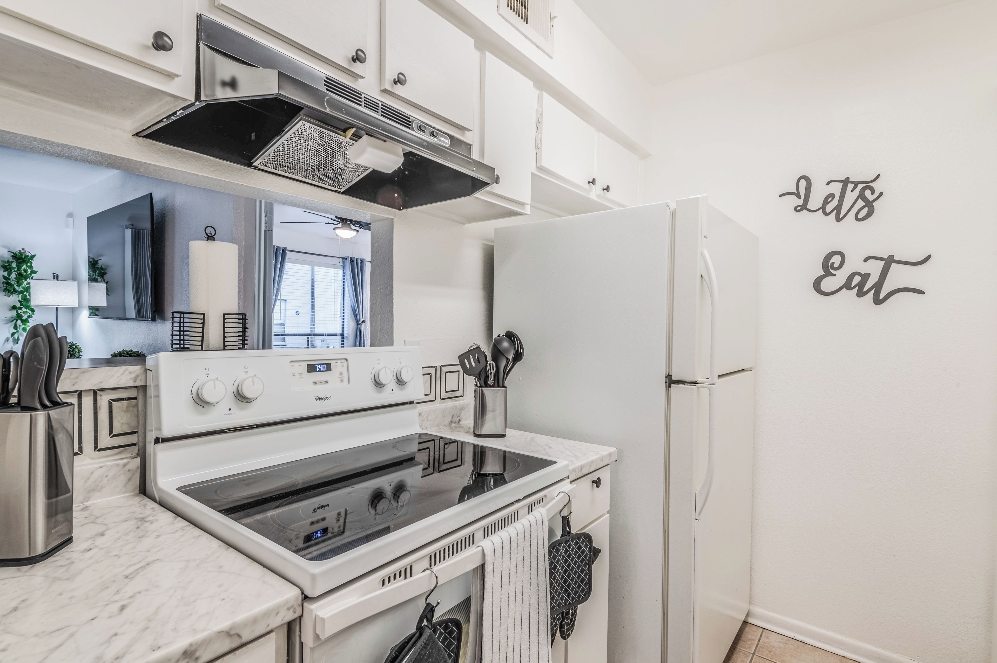Een moderne keuken met witte kastjes, een ingebouwde oven en een koelkast.