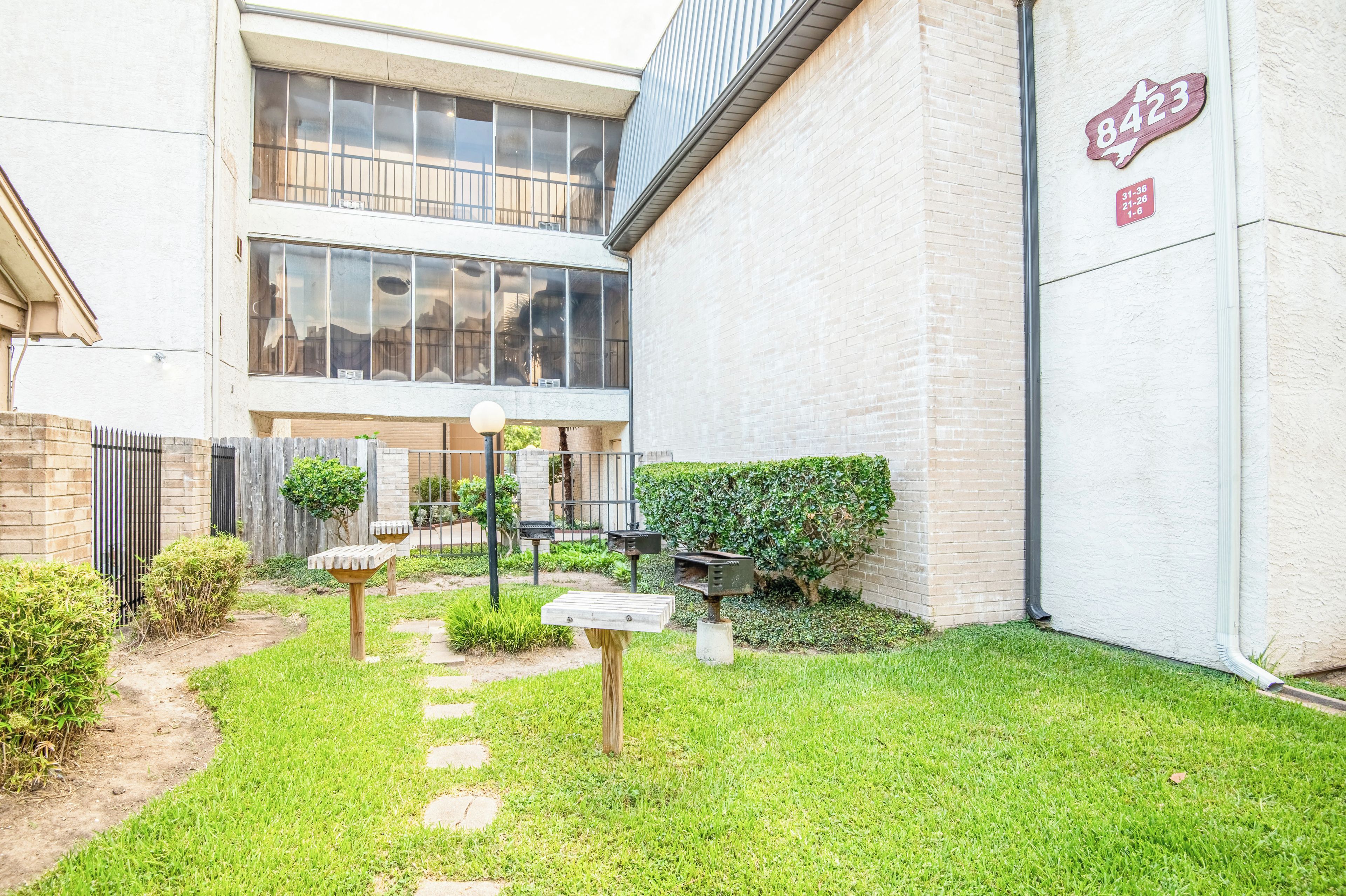 A courtyard with a pathway, a small garden, and a building with a sign indicating the number 8423.
