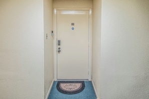 Una porta amb un tancament de codi, un rell d'entrada i un estora amb la paraula 'WELCOME'.