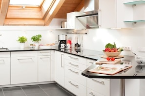 A modern kitchen with white cabinets, a black countertop, and a skylight above. - Holiday apartment with 2 bedrooms (Oberstdorf)