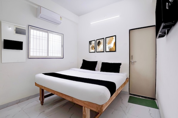 Quarto com cama, janela, ar-condicionado e três quadros na parede.
