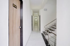A hotel corridor with a wooden door marked '101', a marble floor, and a staircase with metal railings.