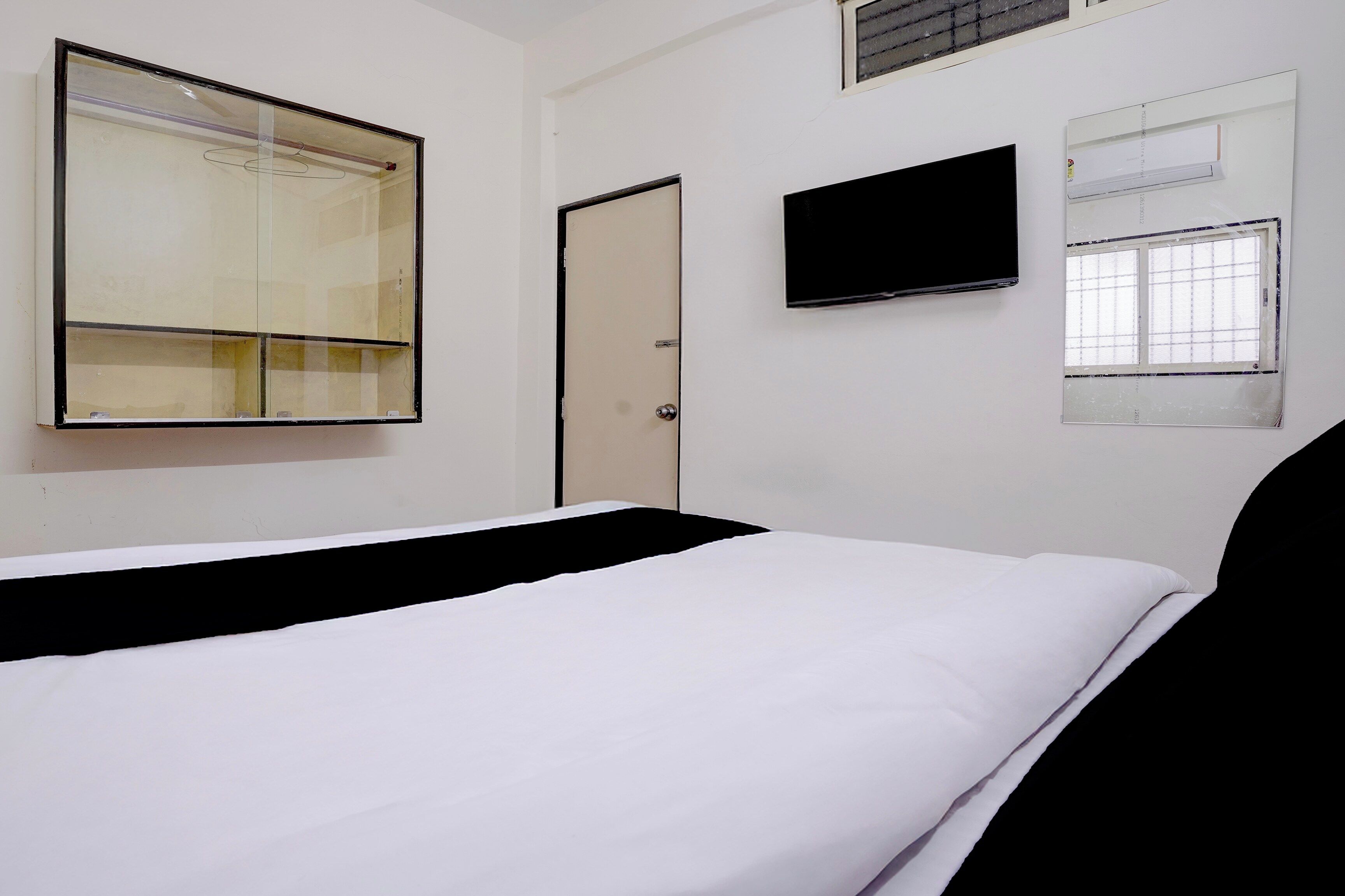 Ein Zimmer mit einem Bett, einem Kleiderschrank, einem Fernseher und einem Fenster.