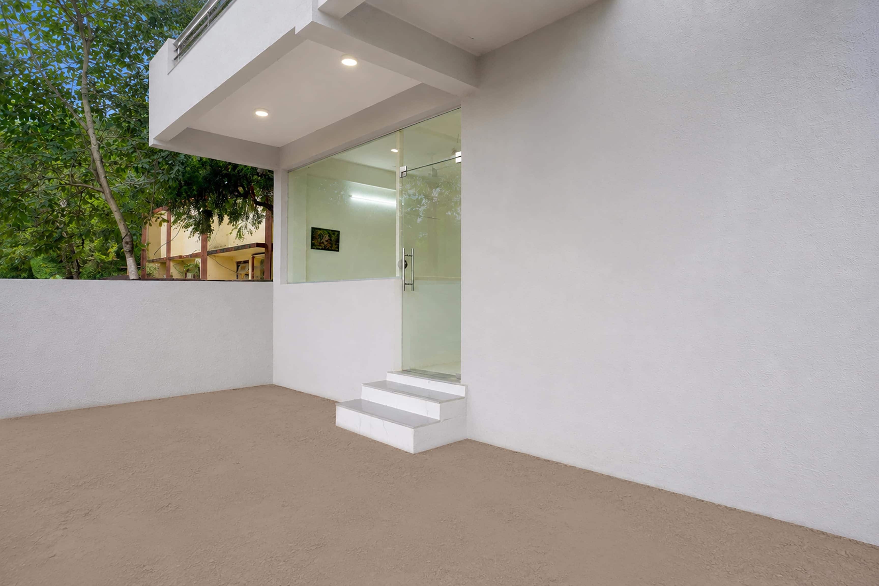 A modern architectural design with a glass door entrance and a set of white steps leading to a covered area.