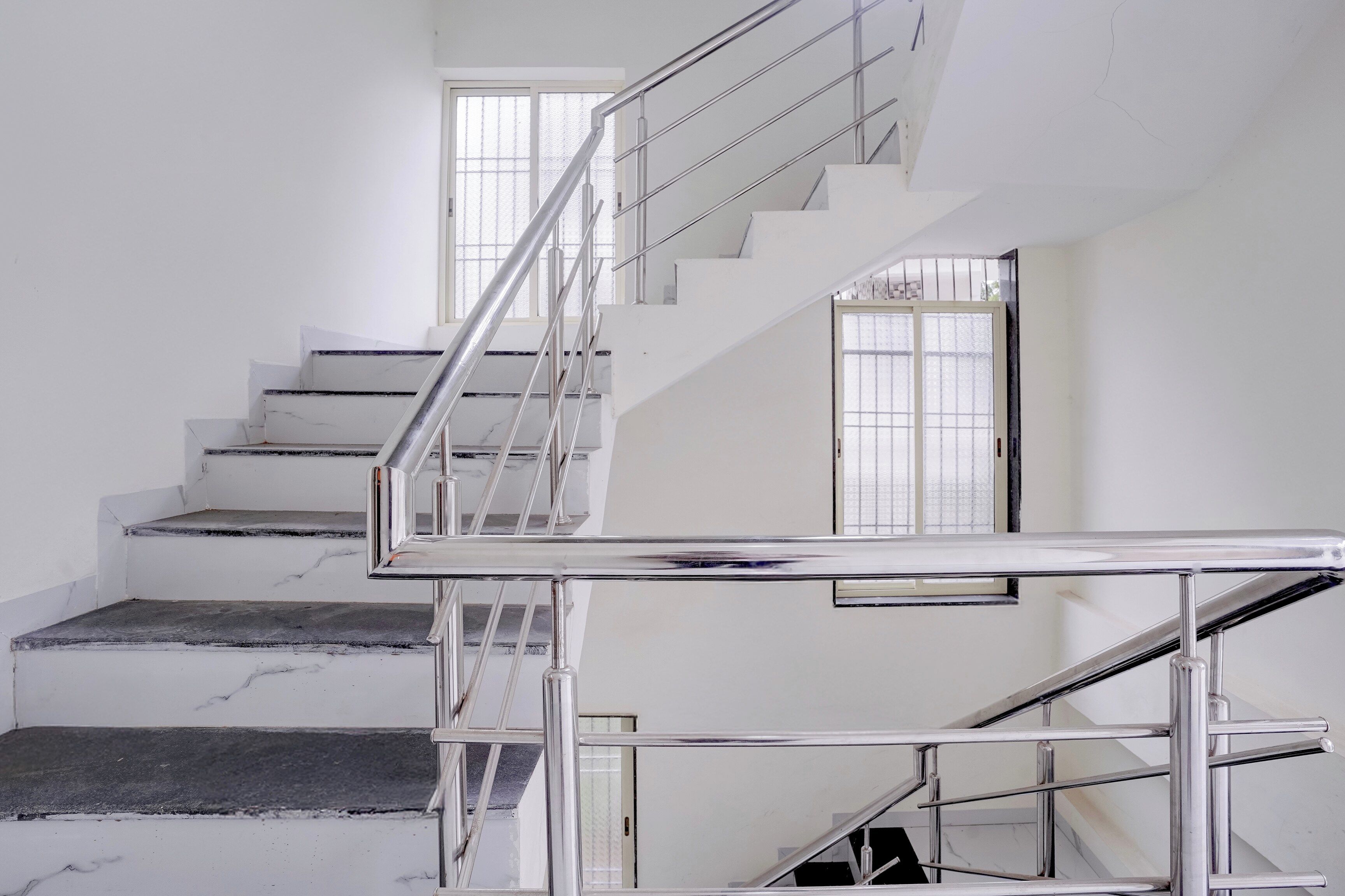 A staircase with metal railings and a marble floor.