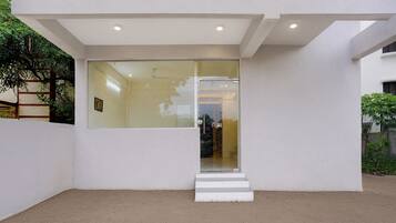A modern building with a glass entrance, white walls, and a concrete ground.