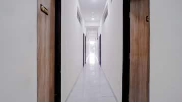 A hallway with two doors, each marked with a number. The floor is tiled, and the walls are white.