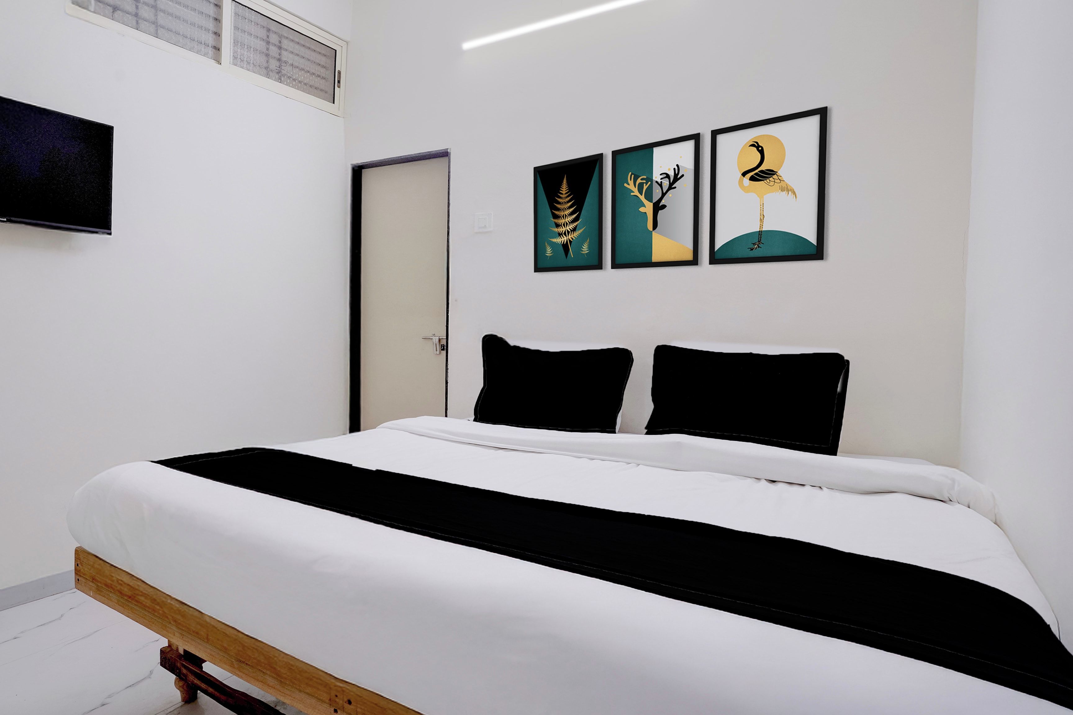 A bedroom with a bed, a door, and three framed pictures on the wall.