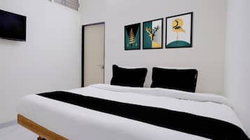 A bedroom with a bed, a door, and three framed pictures on the wall.