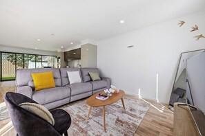 A modern living room with a grey sofa, a wooden coffee table, and a black armchair. - Chic & Fresh: Newly renovated home retreat (Orange)