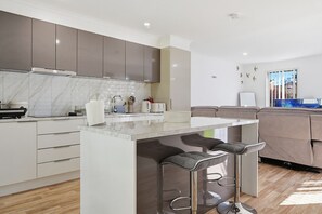 Una cocina moderna con encimera de mármol, electrodomésticos de acero inoxidable y una zona de bar con taburetes.