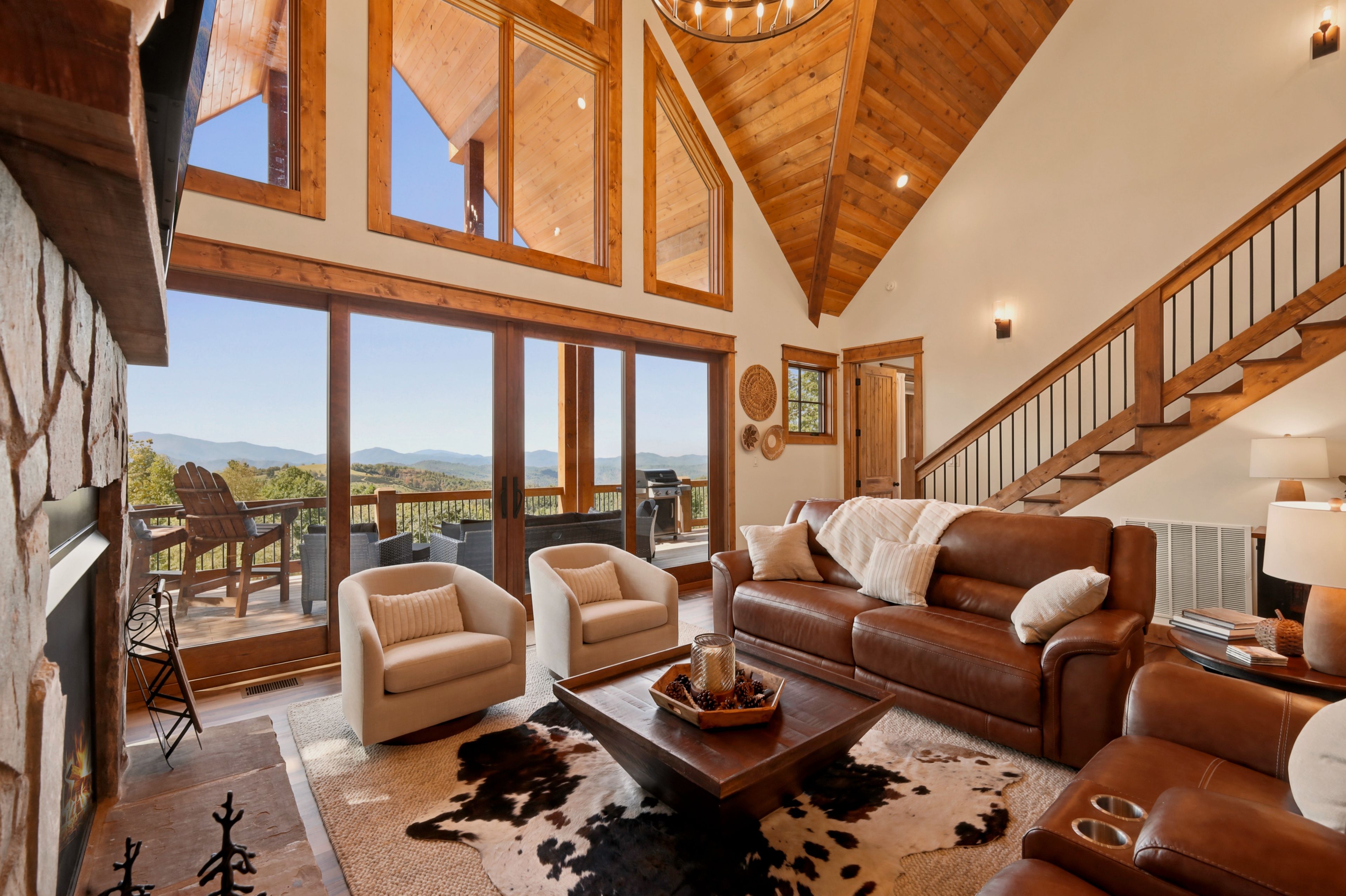 A spacious living room with a high ceiling, large windows, and a view of the outdoors.
