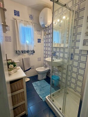 Ein Badezimmer mit Glasdusche, Waschbecken in Weiß und Toilette.