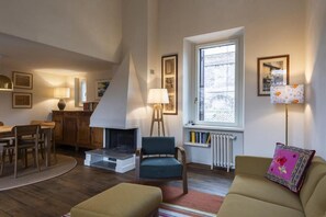 A cozy living room with a fireplace, a dining area, and a window with a view. - Trastevere Luxury Panoramic Terrace (Roma)