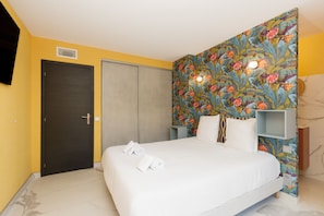 A hotel room with a bed, a wardrobe, a headboard with floral wallpaper, and a small shelf unit. - 3 bedrooms, 2 bathrooms, balcony, garage A3B139 (Cannes)
