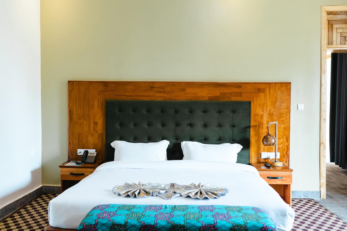 A hotel room with a large bed, two bedside tables, a telephone, and a lamp.